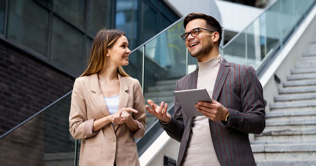 Professional man and woman talking as walk down outdoor stairs